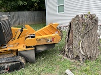 a small tractor is being used to remove a tree stump