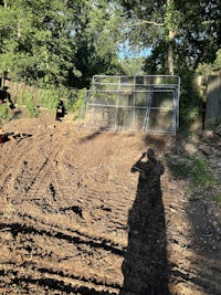 a person standing in the dirt next to a metal fence